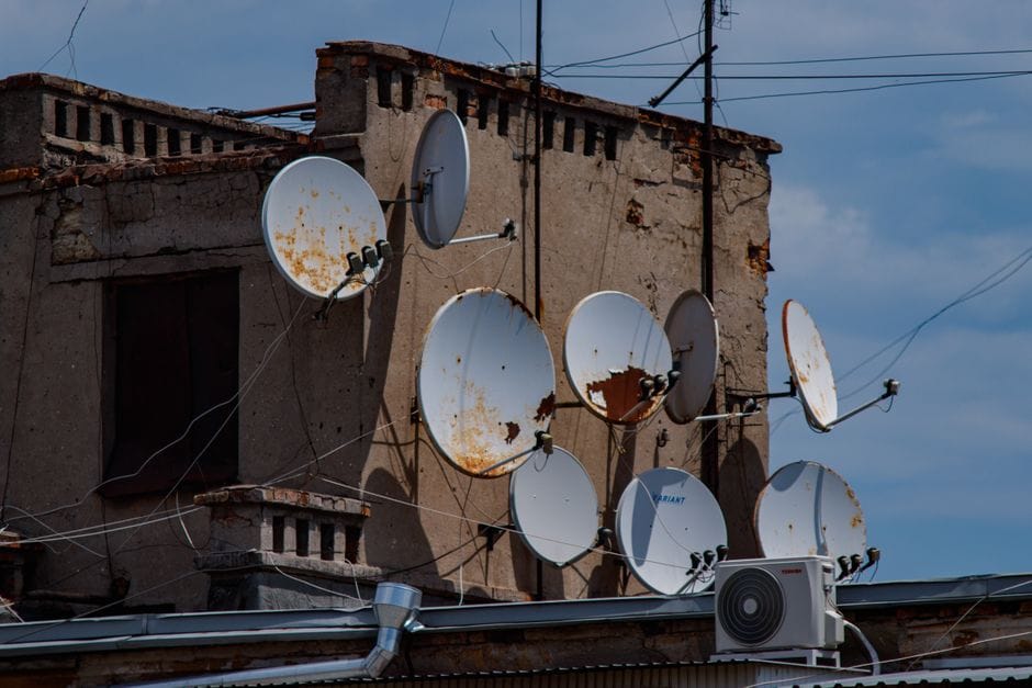 technik sprawdzający stan instalacji antenowej na dachu budynku